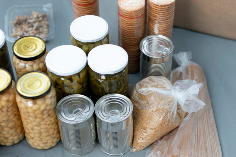 Vorratslagerung mit haltbaren Lebensmitteln in Gläsern und Dosen: Eingelegte Bohnen, Oliven, Artischocken, Konserven sowie Reis und Nudeln in Plastikbeuteln – Beispiel für platzsparende und langlebige Krisenvorsorge.